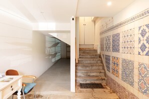A staircase with patterned tiles, a chair, and a desk in a room with white walls and a ceiling light. - VIVA Porto Tile Studios 4T (Porto)