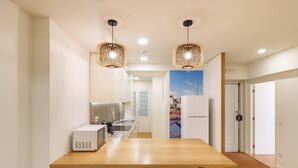 A modern kitchen with a wooden table and bar stools, a microwave, and a refrigerator. - VIVA Casa da Música Apartment (Porto)