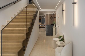 Un área de recepción moderna con una escalera, un mostrador de recepción y un espacio de descanso.