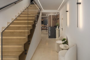 Un área de recepción moderna con una escalera, un mostrador de recepción y un espacio de descanso.