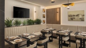 Um restaurante com televisão na parede, painel de madeira e uma pintura de um porto.