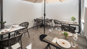 Un comedor con mesas, sillas y sombrillas.