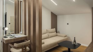 Una habitación moderna con un escritorio de madera, un sofá color beige y una mesa de centro negra.