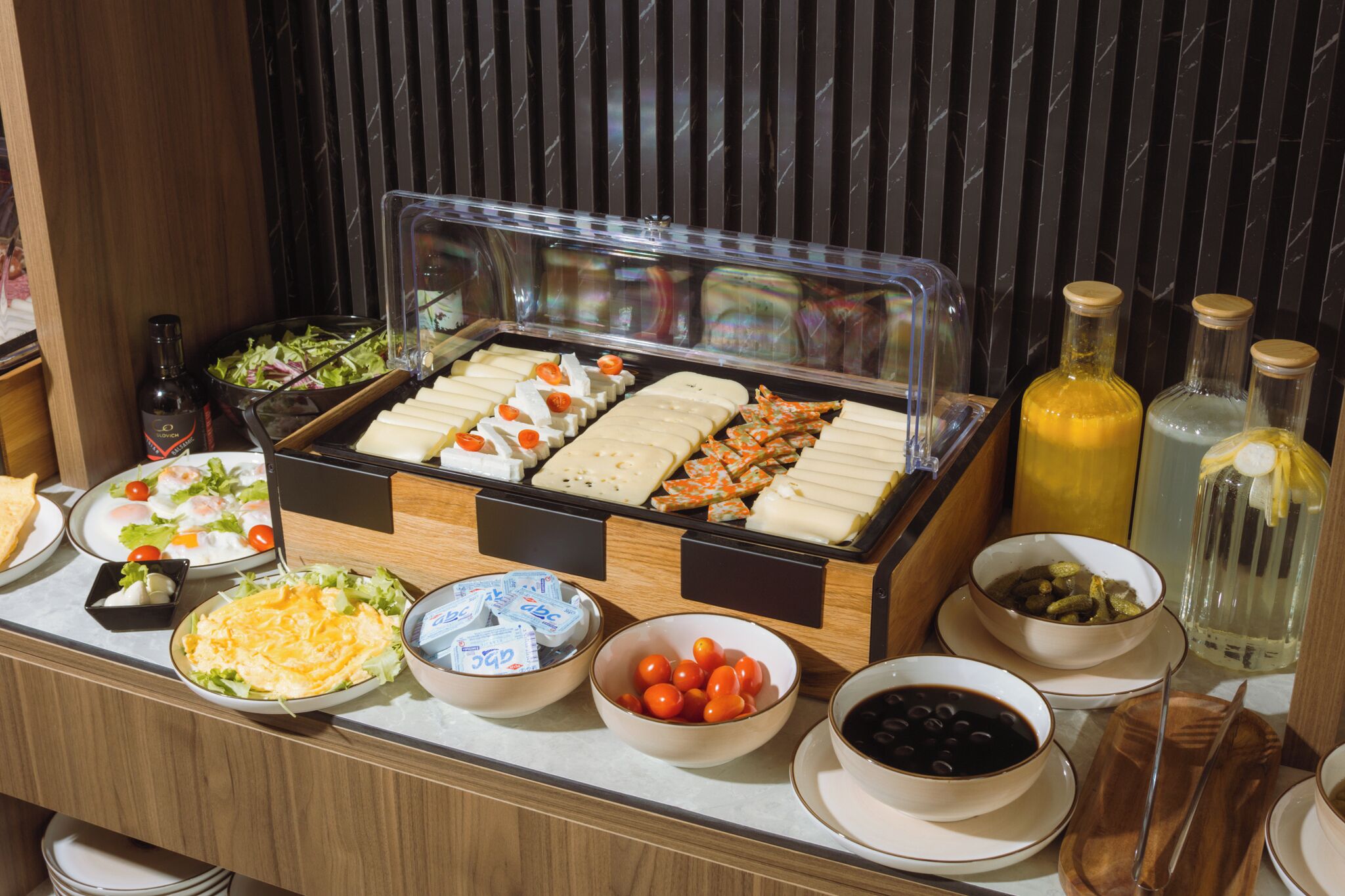 Un buffet proposant une variété de plats, notamment du fromage, des œufs et des salades, ainsi que des accompagnements comme des olives et des cornichons.