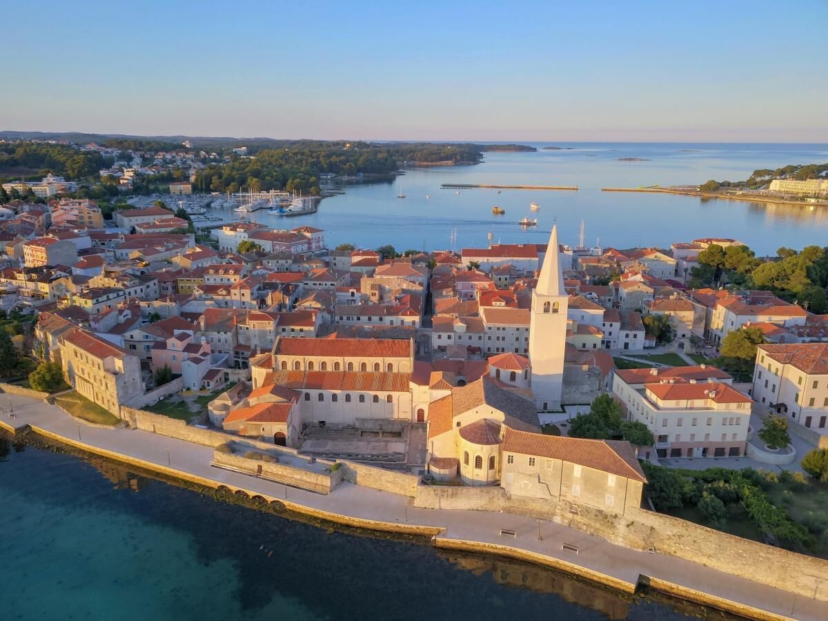 Vue aérienne d’une ville côtière, avec ses bâtiments historiques, une église imposante et une promenade en bord de mer.