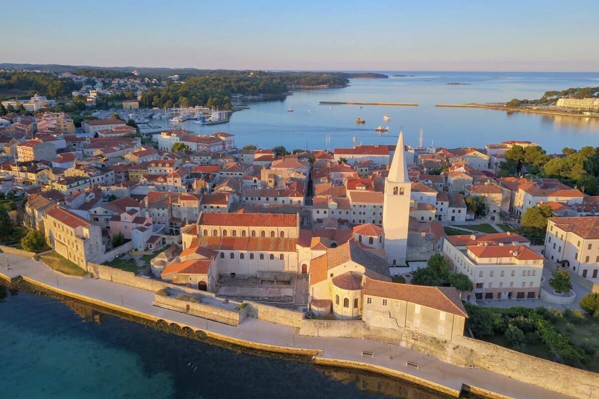Vue aérienne d’une ville côtière, avec ses bâtiments historiques, une église imposante et une promenade en bord de mer.