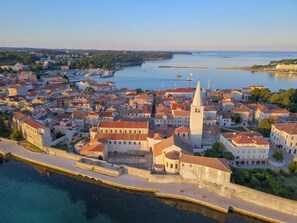 Vue aérienne d’une ville côtière, avec ses bâtiments historiques, une église imposante et une promenade en bord de mer.