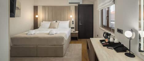 Una habitación de hotel con cama, mesita de noche, escritorio con lámpara y ventana.