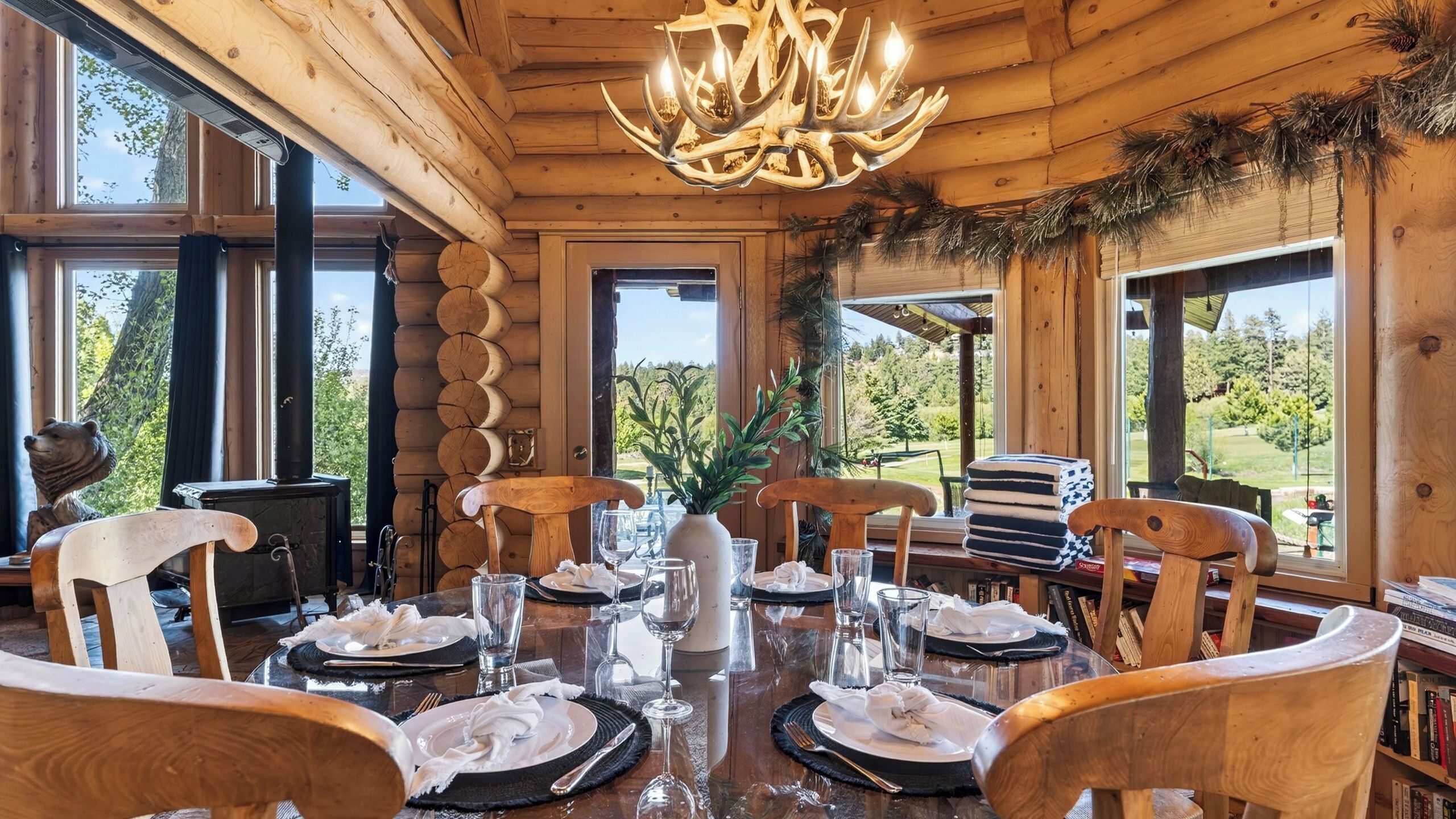 Un comedor de madera con candelabro, mesas redondas y sillas.