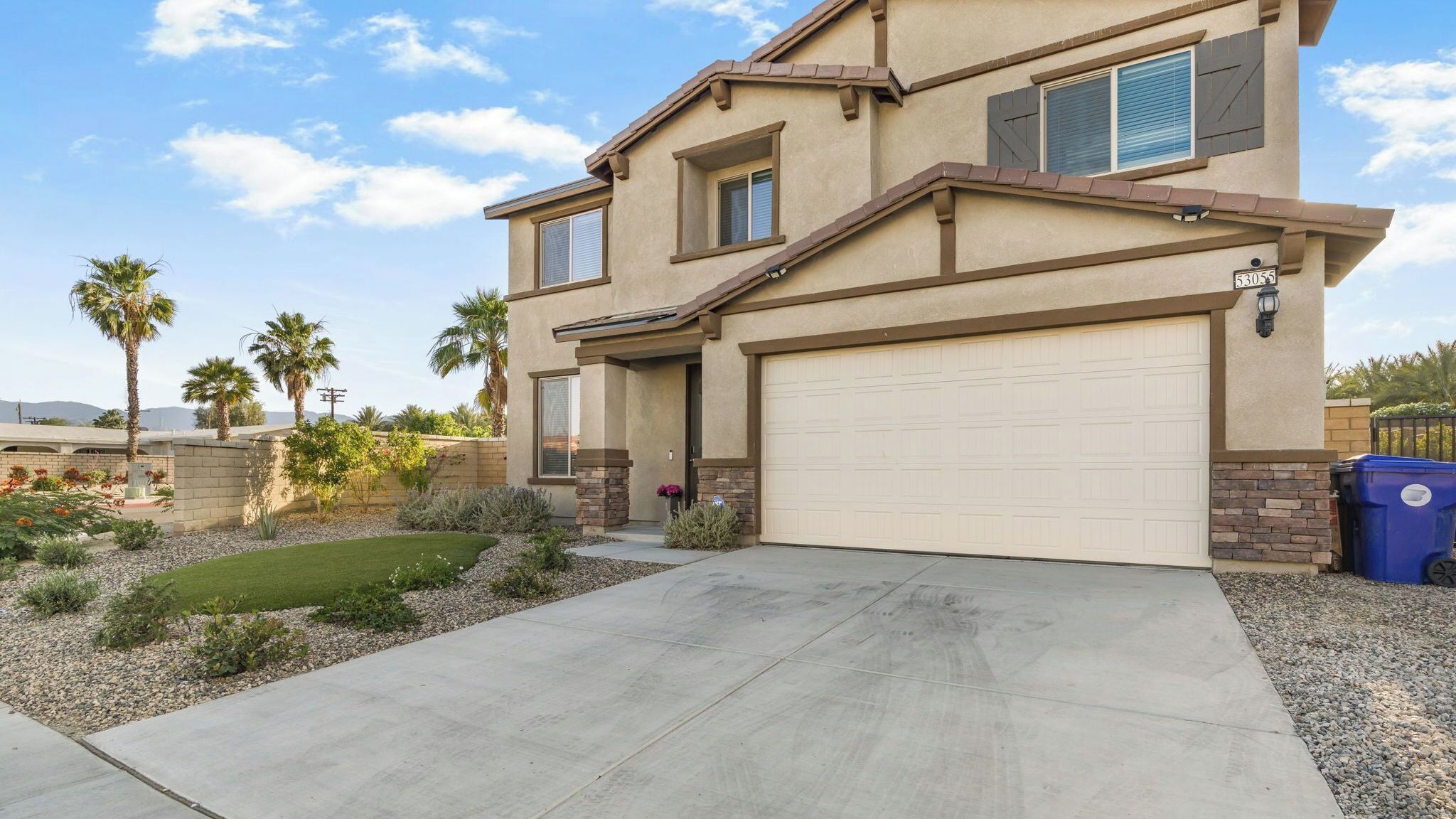 A two-story house with a garage, a well-maintained lawn, and a clear sky.