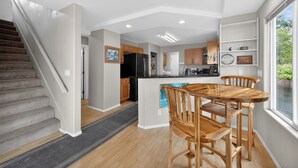 Eine moderne Küche mit Holzschränken, einem schwarzen Kühlschrank und einem Essbereich mit Holztisch und Stühlen.