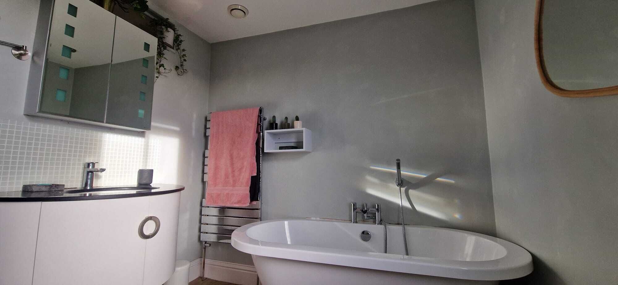 A bathroom with a white bathtub, a sink with a mirror, and a towel rack.