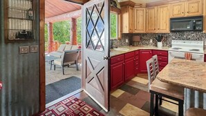 Una cucina con mobili in legno, un forno a microonde, un fornello e un'area pranzo con tavolo e sedie.