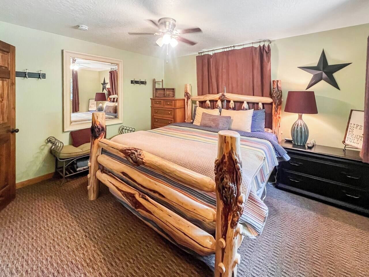 A bedroom with a wooden bed, a ceiling fan, a dresser, a mirror, and a star decoration on the wall.