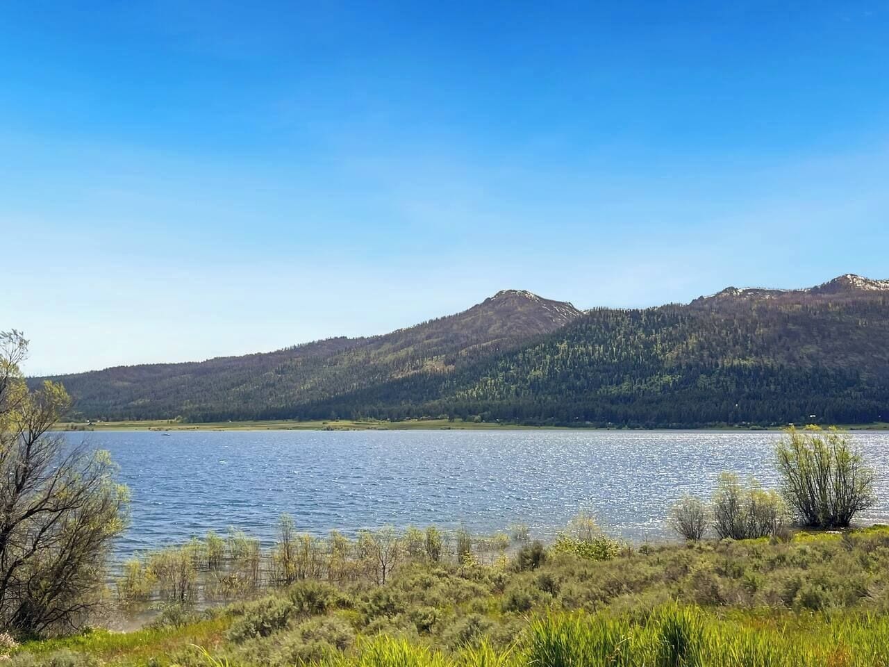 Um lago com montanhas ao fundo e céu claro.