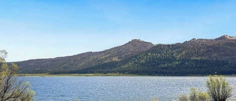 Um lago com montanhas ao fundo e céu claro.