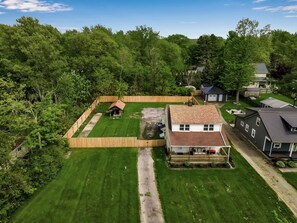 A residential property with a fenced backyard, a wooden deck, a house with a porch, and a small shed.