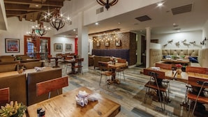 Un restaurant avec des tables et des chaises en bois, un mur en briques et un lustre.
