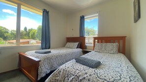 Un dormitorio con dos camas, una ventana y vistas al verde exterior.