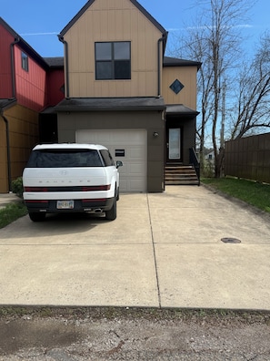 A modern two-story house with a garage, a white SUV parked in front, and a clear sky.