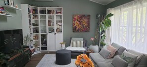 Ein Wohnzimmer mit Bücherregal, einer Couch, einem Couchtisch und einem Bild an der Wand.