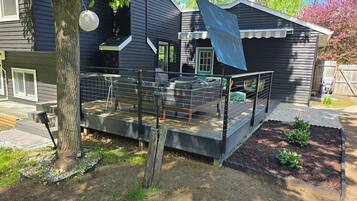 Une maison avec une terrasse, un espace clôturé et un petit jardin.