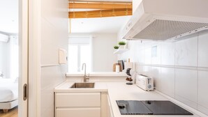 A modern kitchen with a built-in dishwasher, a sink, a toaster, and a tablet on the counter. - Loft-style apartment in the El Pópulo district (Ciudad de Cádiz)