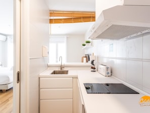 Eine moderne Küche mit Einbaugeschirrspüler, Spüle, Toaster und einem Tablet auf der Arbeitsfläche.