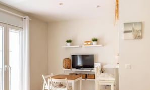 Ein modernes Wohnzimmer mit einem Flachbildfernseher, weißen Möbeln und Dekorationen in Regalen.