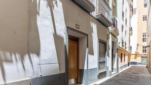 A narrow cobblestone street with buildings on either side, a wooden door, and a metal gate. - Loft-style apartment in the El Pópulo district (Ciudad de Cádiz)