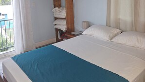 Makuuhuone, jossa on sänky, puinen hylly, yöpöytä ja ikkuna, jossa on verhot.