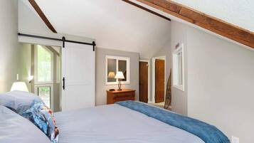 Un dormitorio con cama, mesita de noche, lámpara, puerta corredera y ventana.