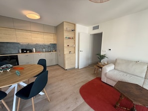 Eine moderne Küche mit Holzsäcken, einem Esstisch mit Stühlen, einem roten Teppich und einem gestreiften Sofa.