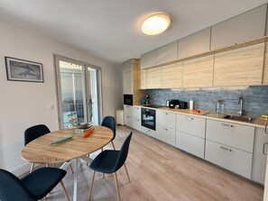 Eine moderne Küche mit Essbereich, mit einem runden Tisch, Stühlen und Blick durch eine Glastür.