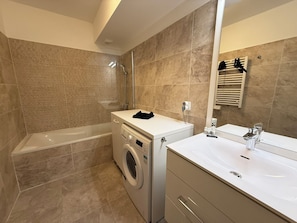 Ein modernes Badezimmer mit einer Badewanne, einer Waschmaschine und einem Waschbecken.