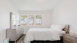 Ein Schlafzimmer mit Bett, Schminktisch und Fenster.