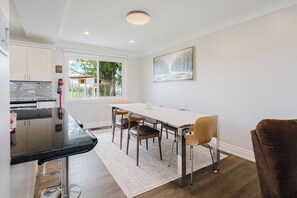 A modern kitchen with a bar area, a dining table with chairs, and a large window with a view of greenery. - Private room in ottawa (Ottawa)