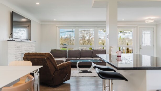 Ein modernes Wohnzimmer mit Sofa, Esstisch und Küchenzeile mit Bar.