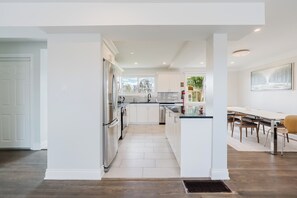 A modern kitchen with white cabinetry, stainless steel appliances, and a dining area with a table and chairs. - Private room in ottawa (Ottawa)