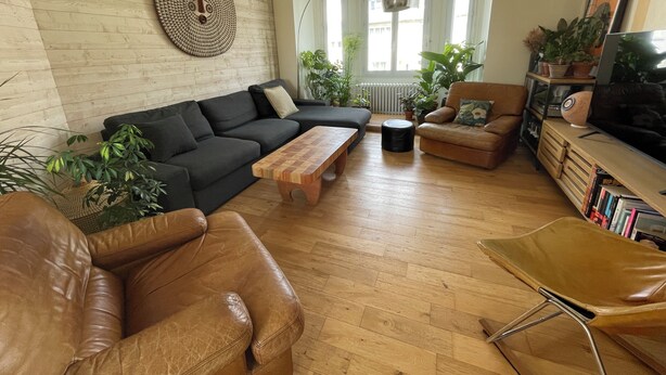 En stue med sofa, lænestol, sofabord og et fjernsyn på et træskab.