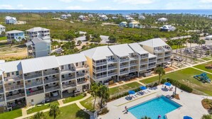 A multi-story hotel with balconies, a swimming pool, and a view of the ocean. - The Mystic Turtle at Cape San Blas (Port St. Joe)