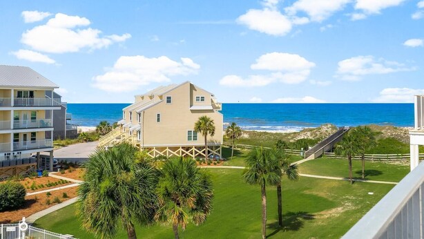 A beachfront hotel with a two-story building, a grassy lawn, and a view of the ocean. - The Mystic Turtle at Cape San Blas (Port St. Joe)