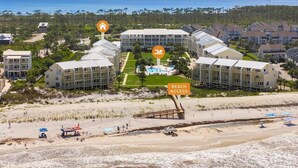 A coastal hotel with multiple buildings, a beach access sign, and a pool area. - The Mystic Turtle at Cape San Blas (Port St. Joe)