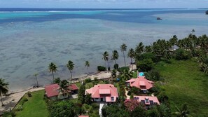 A coastal property with multiple buildings, a beach, and palm trees.