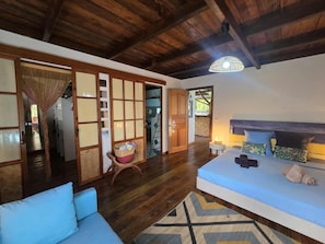 A room with a bed, a sofa, a wooden ceiling, and a view of the outside. - Villa Fareatai (Raiatea)