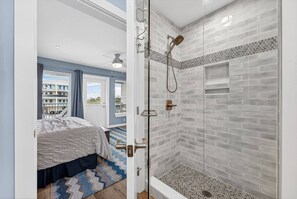 Ein Schlafzimmer mit einem Bett, einer Dusche mit Glastür und Blick auf Gebäude.