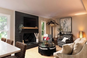 Ein Wohnzimmer mit Kamin, einem Esstisch und zwei Sofas.