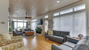 Un salon spacieux doté d’un ventilateur de plafond, de grandes fenêtres et d’une cheminée.