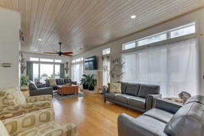 Ein geräumiges Wohnzimmer mit Deckenventilator, großen Fenstern und Kamin.