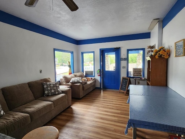 A room with a brown sofa, a blue table, and a blue door. - Cozy Bear Inn (Maggie Valley)